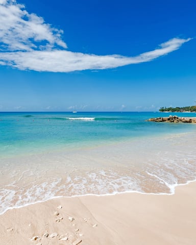 Tropical beach with turquoise water, white sand, palm trees, and clear blue sky with wispy clouds